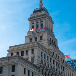 A prominent clock tower atop a large building, surrounded by bare branches and a clear sky from an observation deck perspective.