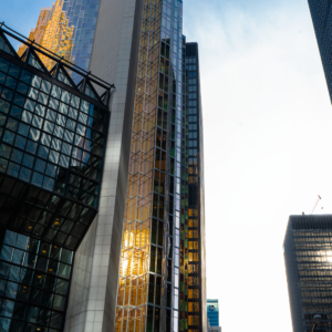 Amidst the city’s towering structures, the glass buildings glisten in the evening light, their sleek surfaces reflecting the sky above.